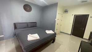 A bedroom with a bed, a wall decoration, a door, and a small table. - Pocket Pillow Patong (Patong)