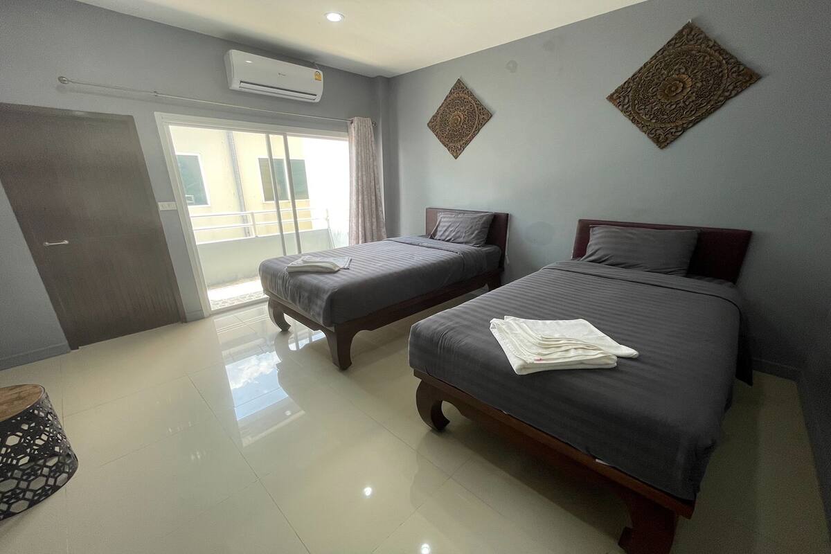 Quarto de hotel com duas camas, uma porta de correr de vidro e arte decorativa na parede.