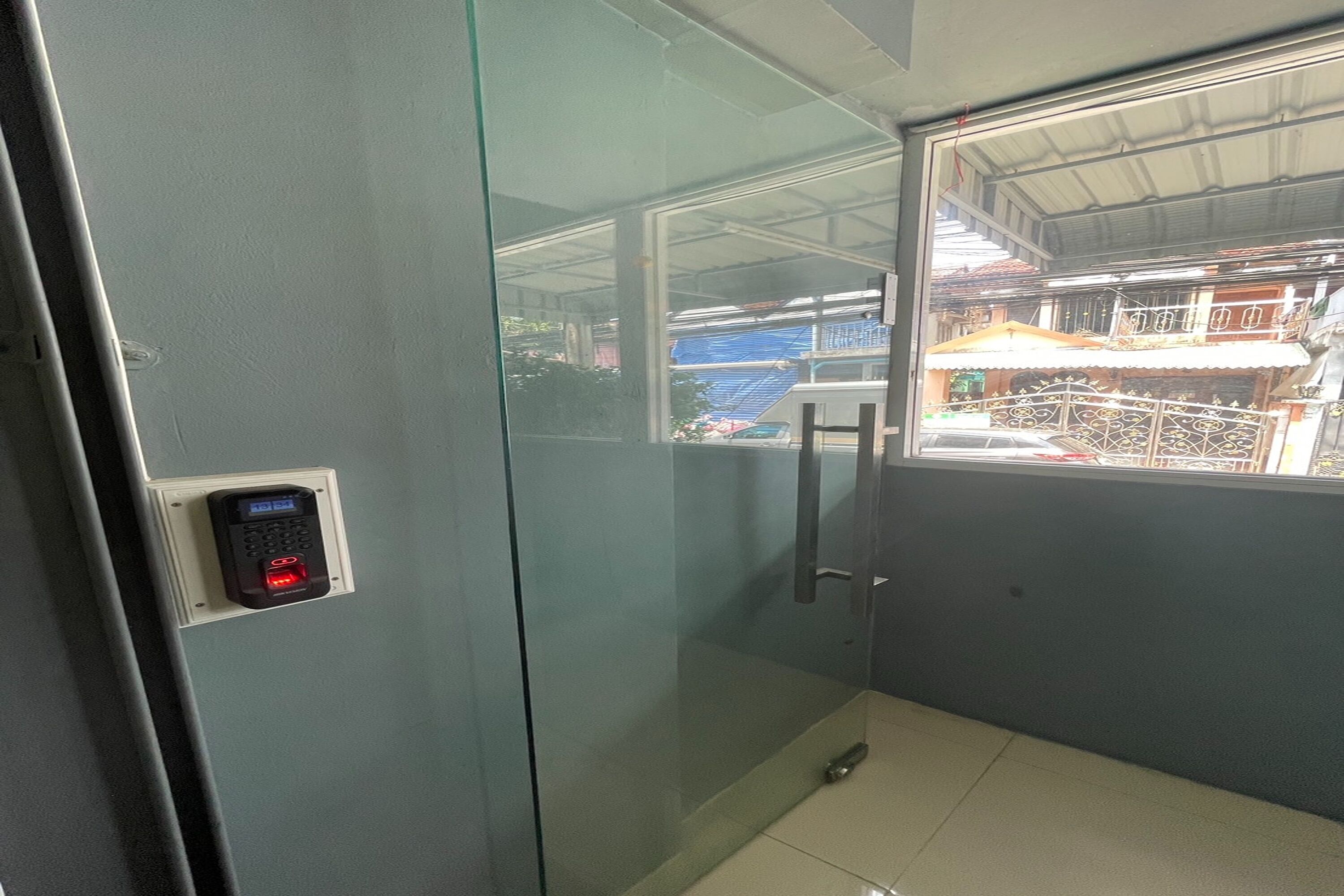A glass-walled room with a digital lock on the door, a small window, and a metal handle.