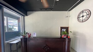 A reception desk with a clock, potted plants, and a window with a view. - Pocket Pillow Patong (Patong)