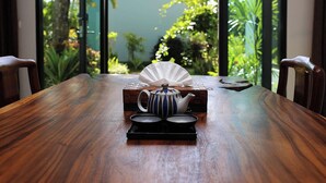 Een houten eettafel met een theepot, twee theekoppen en een gevouwen servet op een dienblad.