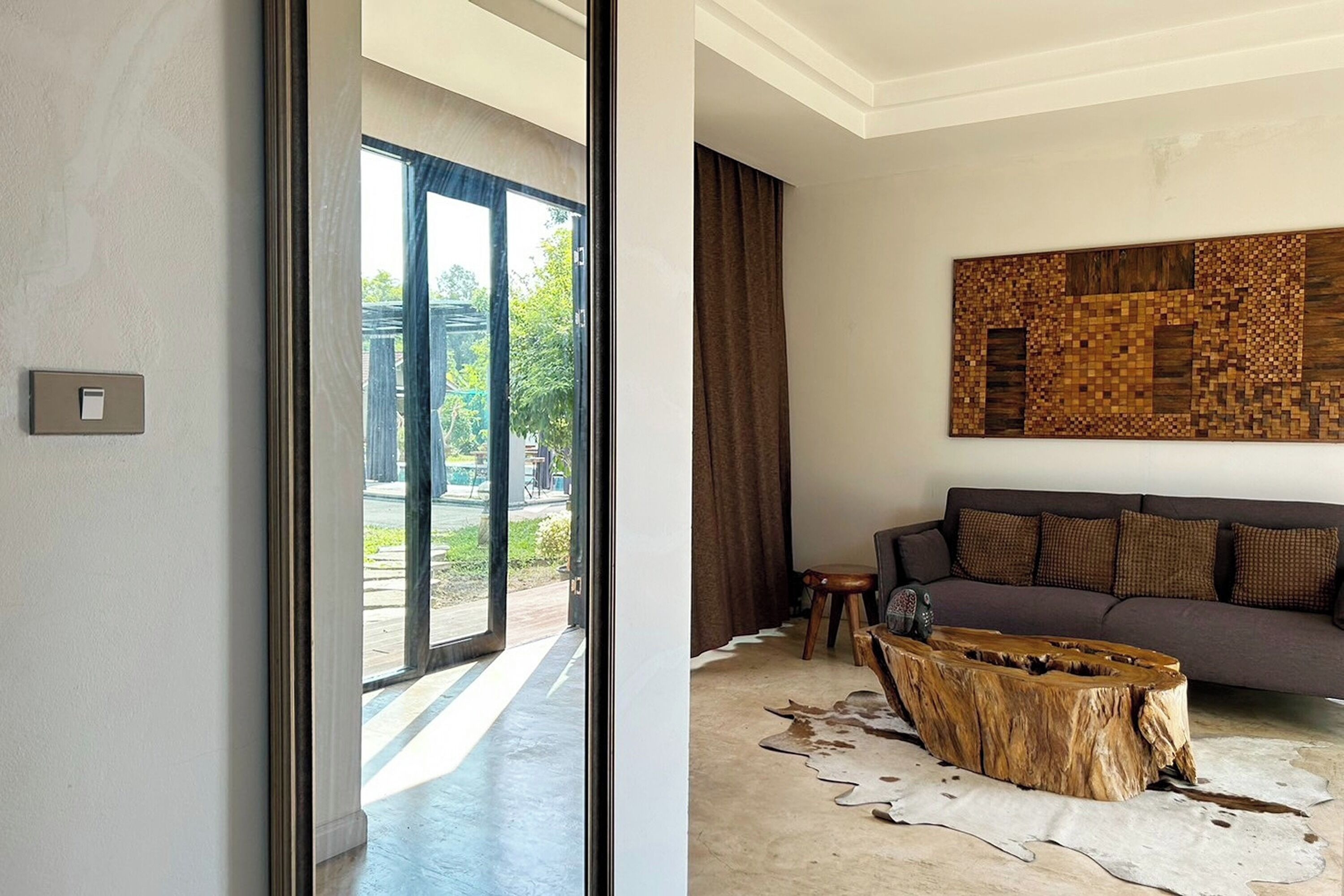 A modern living room with a large window, a sofa, a coffee table, and a wall art piece.
