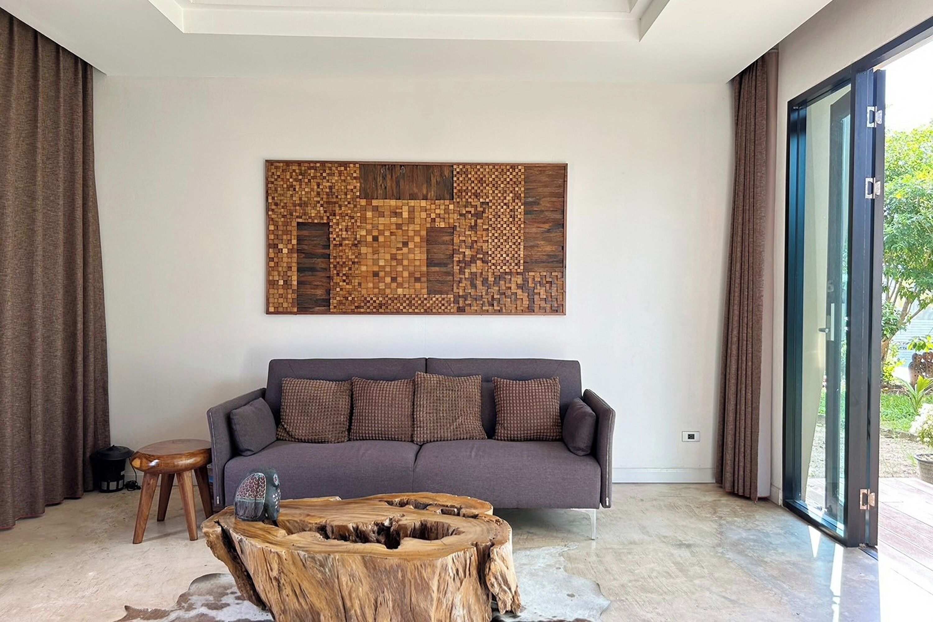 A modern living room with a grey sofa, a wooden coffee table, and a large abstract wall art piece.