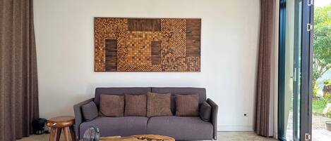 A modern living room with a grey sofa, a wooden coffee table, and a large abstract wall art piece.