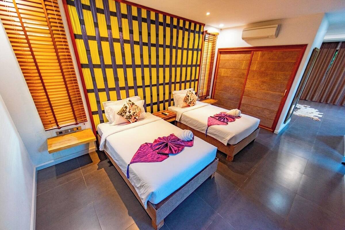 A hotel room with two beds, a wooden headboard, and a large window with blinds.