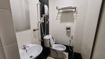 Un baño moderno con un lavamanos blanco, inodoro y ducha de mano montada en la pared.