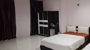 A hotel room with a bed, a wardrobe, a nightstand, and a wall-mounted light fixture.
