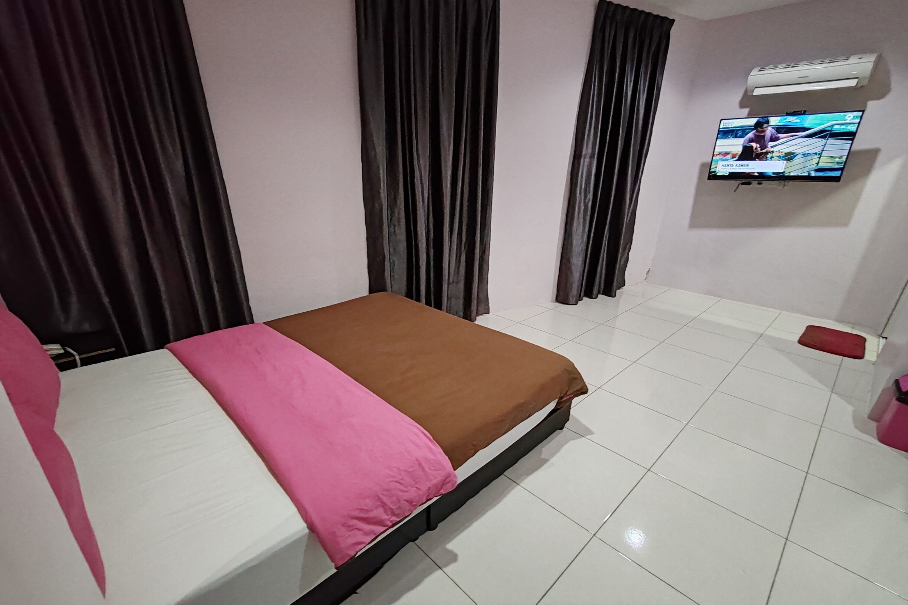 Une chambre d’hôtel équipée d’un lit, de rideaux, d’une télévision et d’un appareil de climatisation.