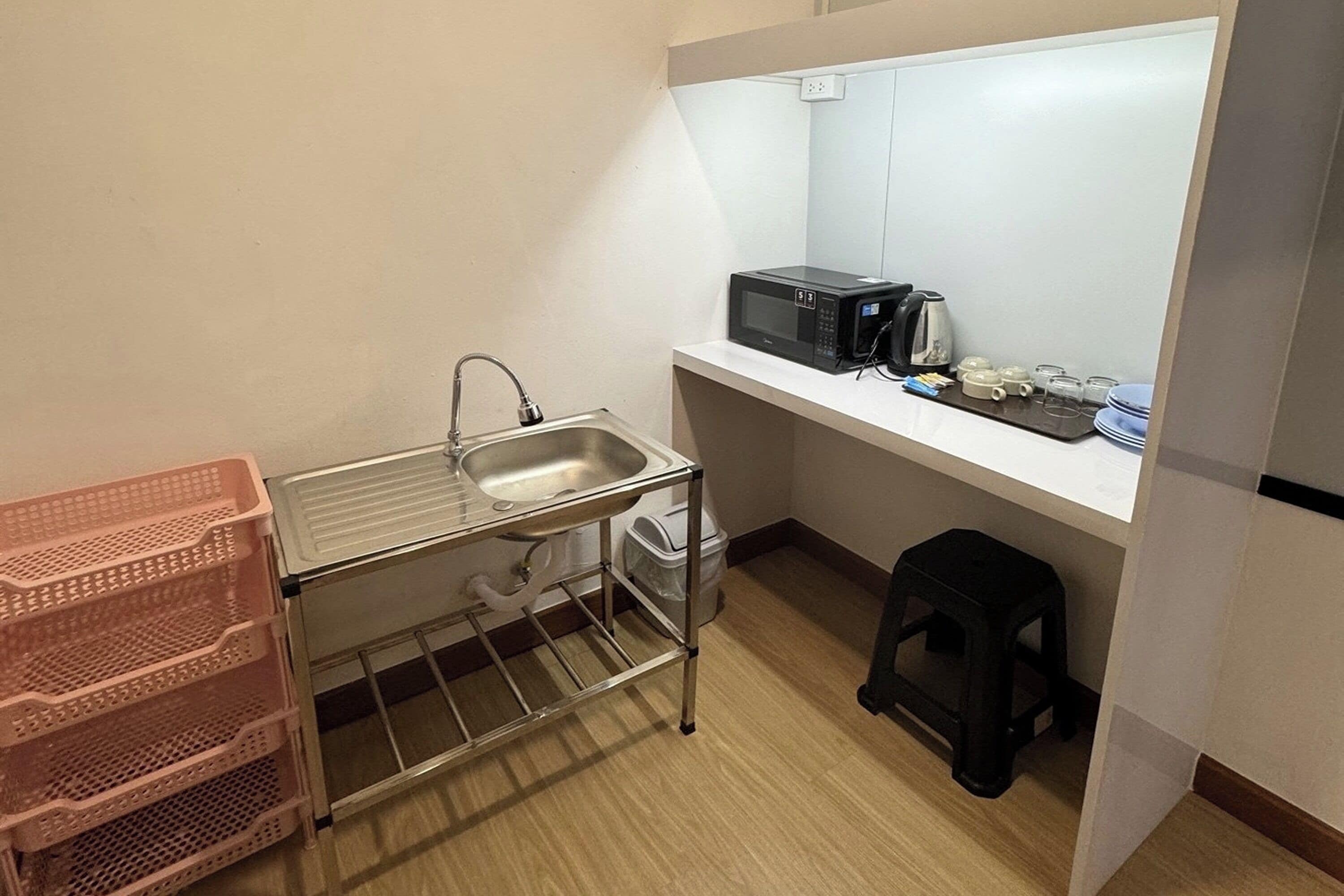 Une petite cuisine équipée comprenant un évier, un four à micro-ondes et un petit tabouret.