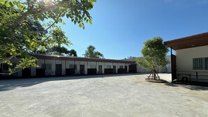 Um pátio amplo com um edifício com várias janelas e uma área coberta para sentar.