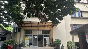 A building with a covered entrance, steps leading up to a door, and various signs. - Sultan Residence Syariah (Jakarta)