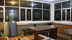A kitchen with a dining area, large windows, and a refrigerator. - Sultan Residence Syariah (Jakarta)
