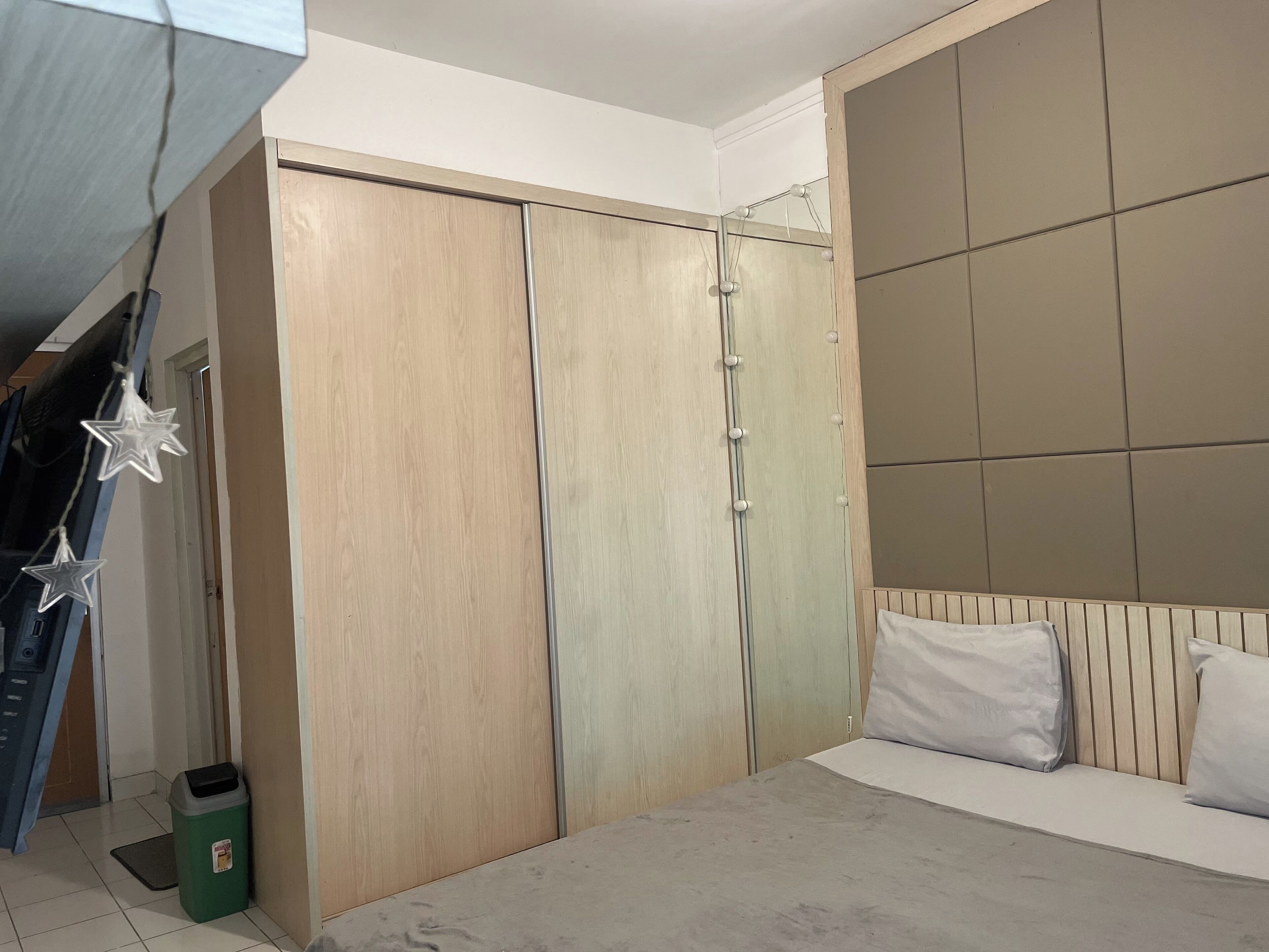 Un dormitorio con cama, armario y espejo con iluminación.