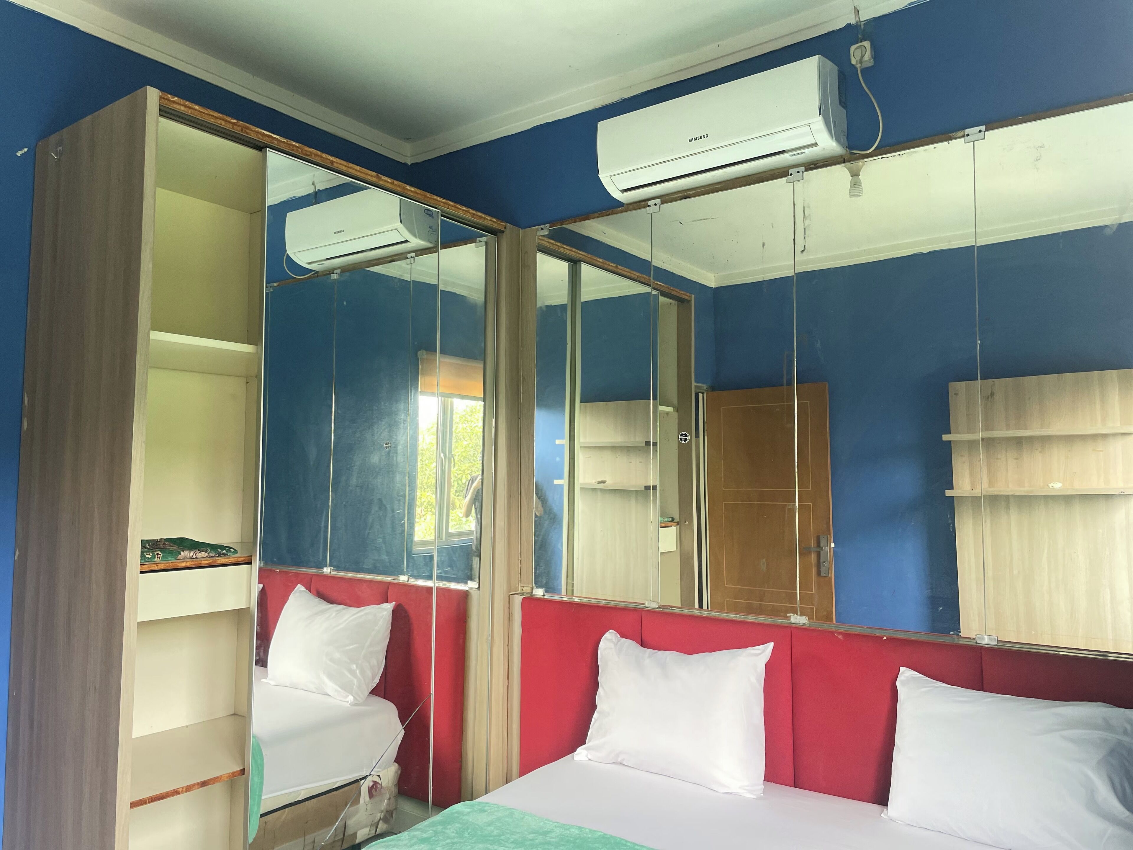 A room with a bed, a wardrobe, and a mirror.