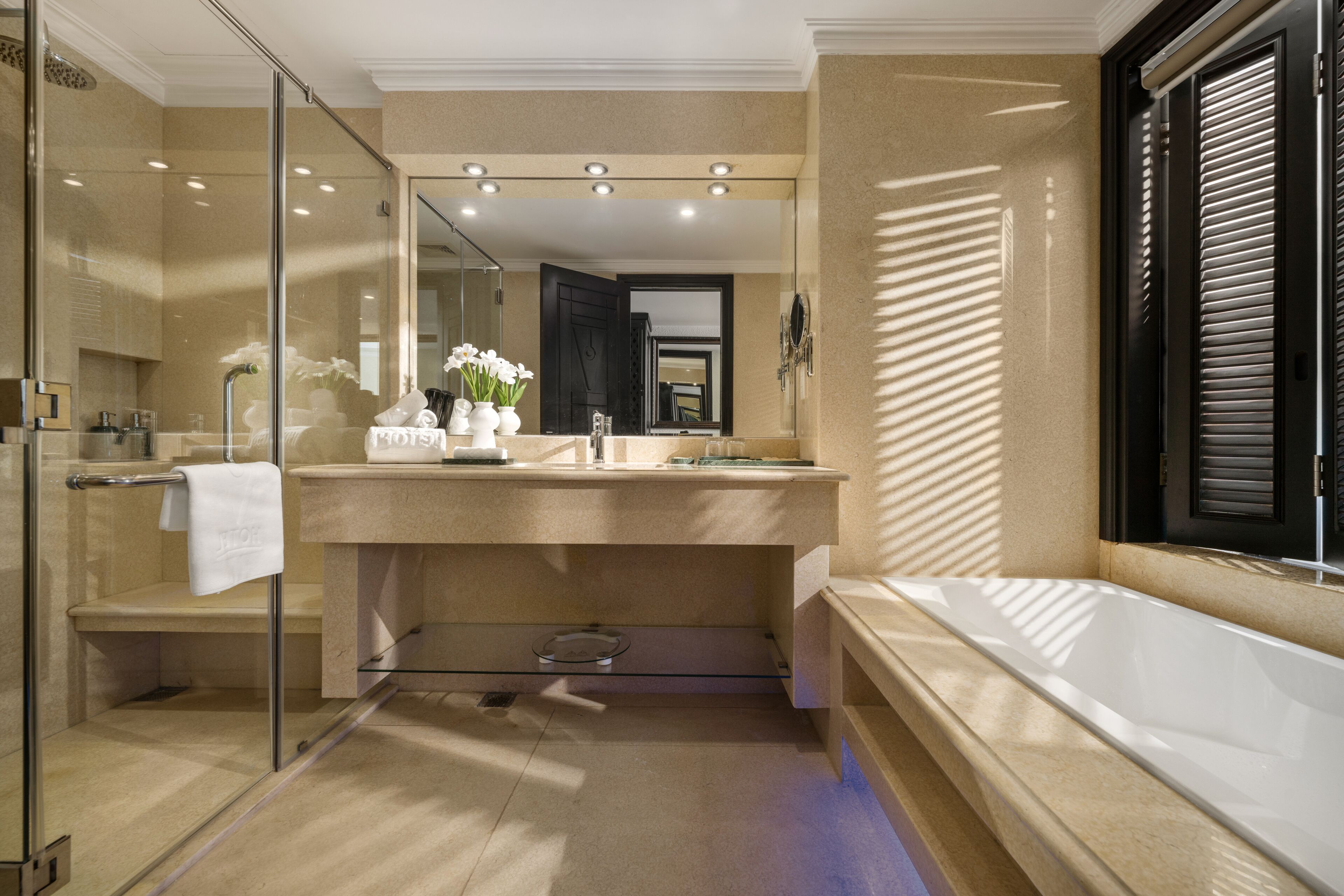 Une salle de bain moderne avec une douche à l’italienne en verre, un grand miroir et une baignoire.