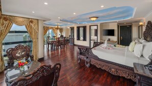 Una habitación amplia con una cama grande, un comedor con mesa y sillas, y vistas por la ventana.