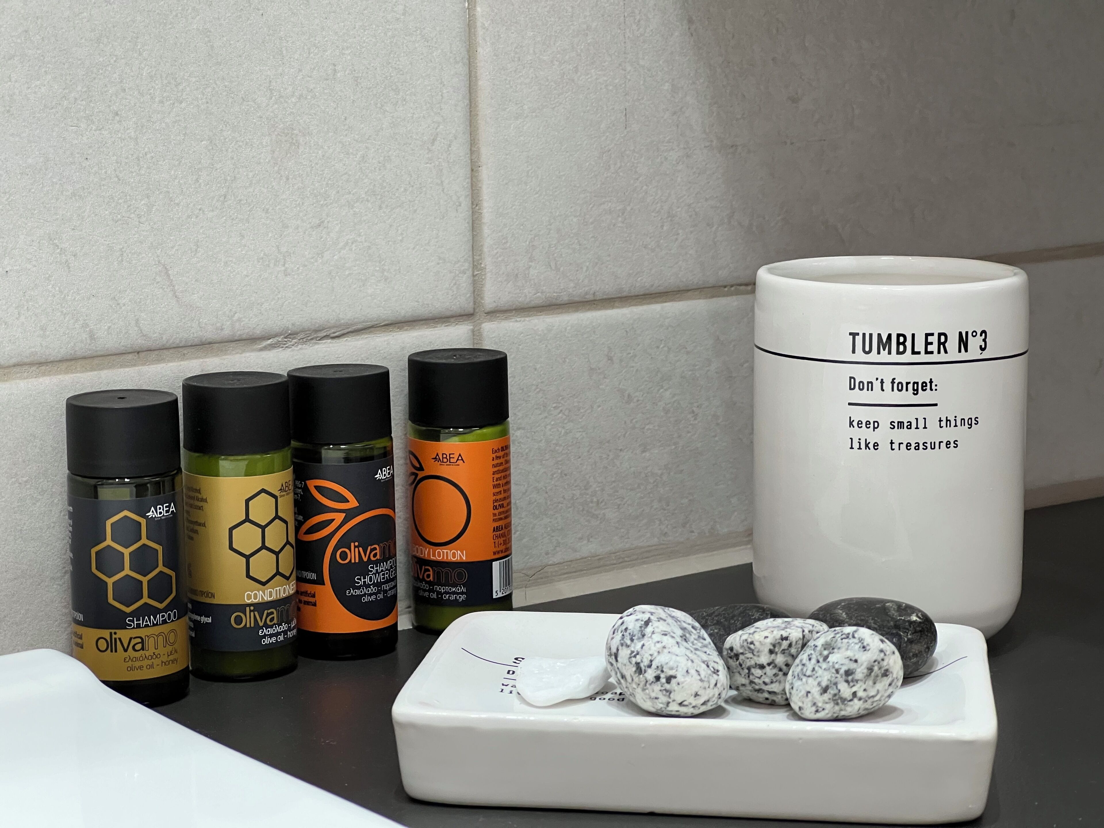 Un taulell de bany amb productes de tocador i un got.
