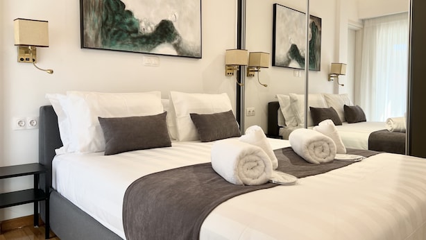 A modern hotel room with a large bed, two bedside tables, a mirror, and artwork on the walls.