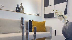 A modern living room with a glass coffee table, a sofa with a mustard-colored pillow, and decorative vases.