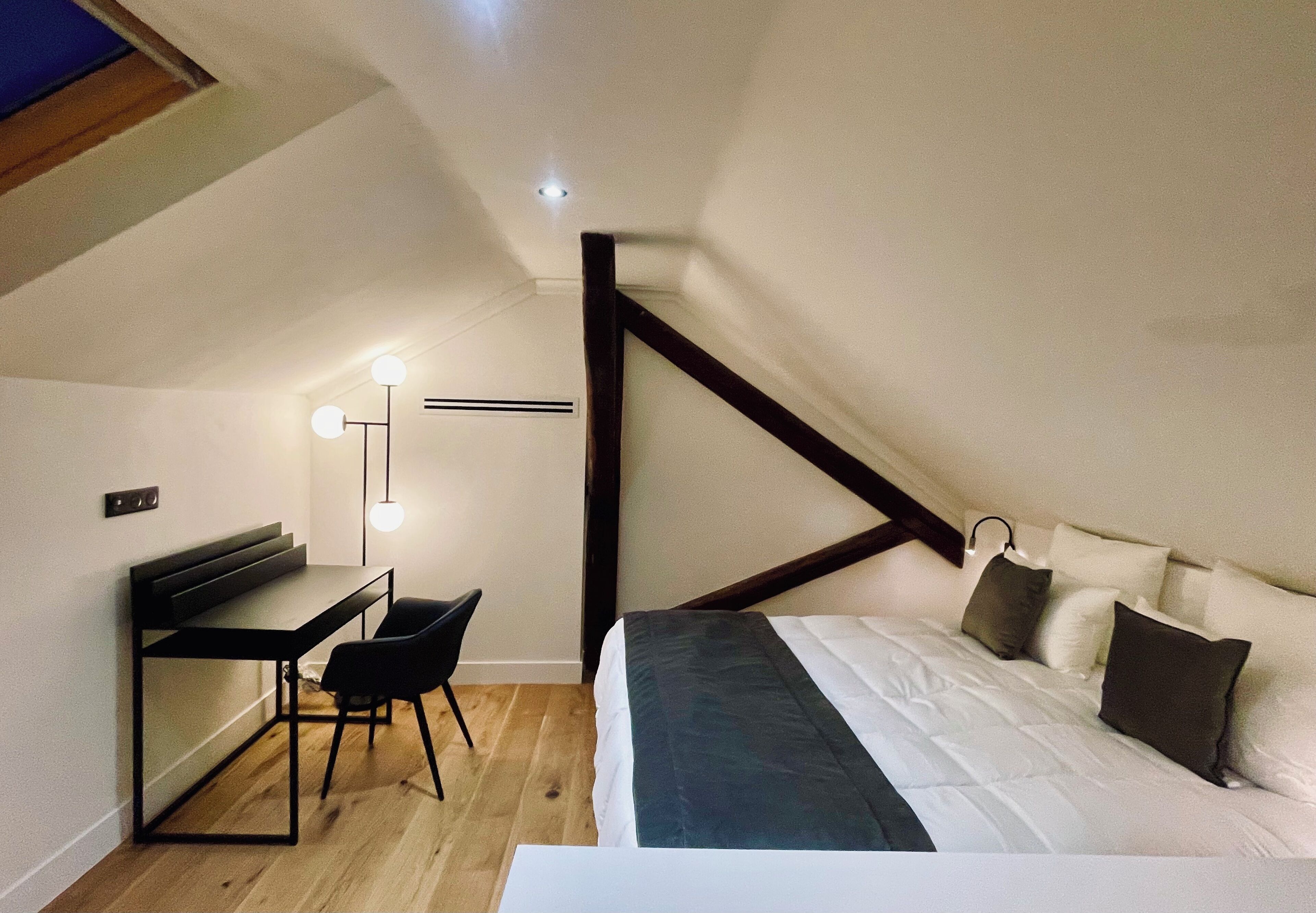 Un dormitorio con cama, mesita de noche y escritorio con silla.