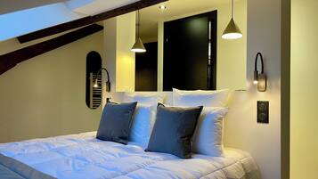 A modern bedroom with a large bed, two wall-mounted lights, and a skylight.
