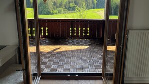 Un balcon ouvert donnant sur un champ verdoyant et des arbres.