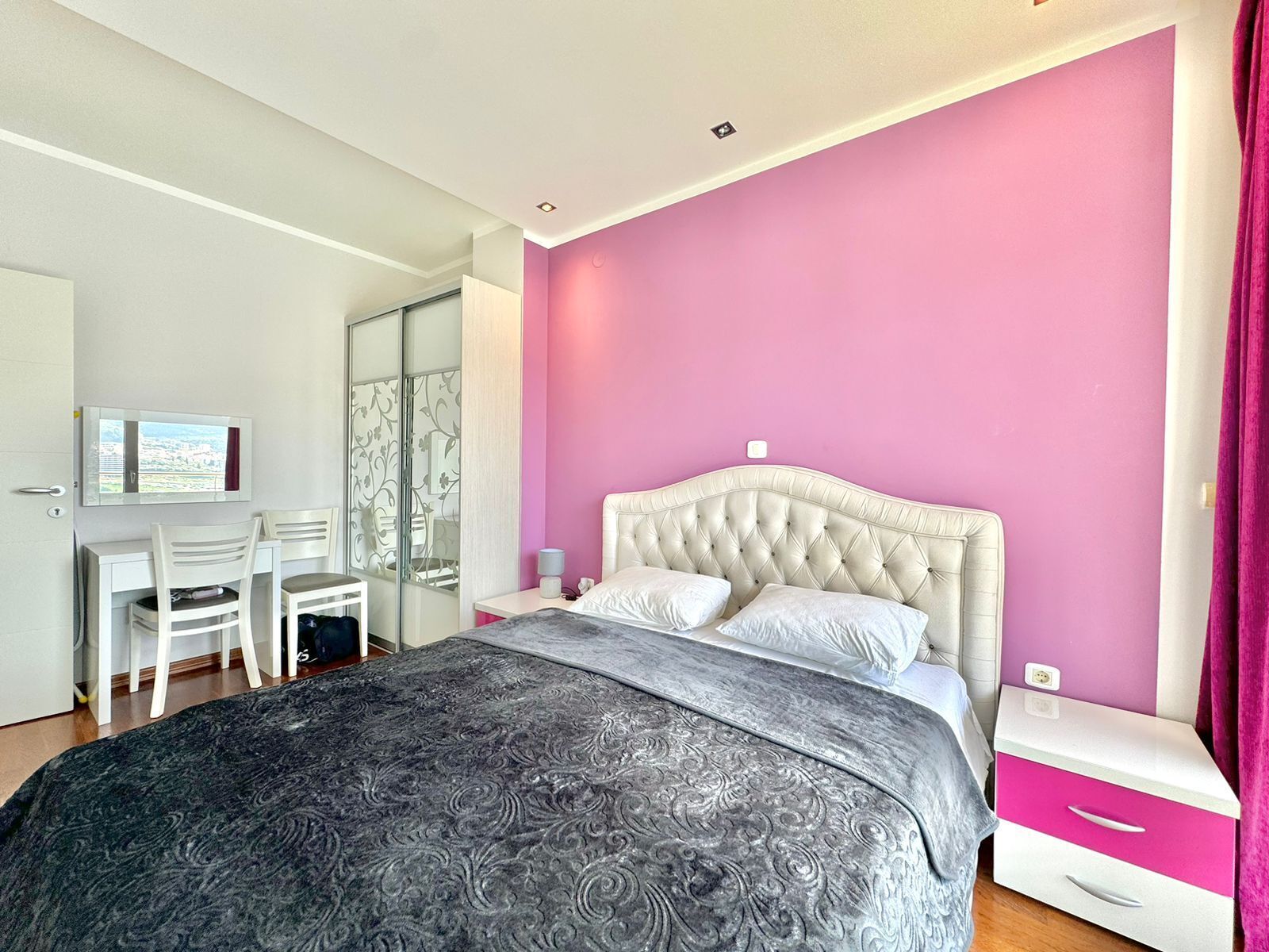 A bedroom with a bed, a desk, and a chair.