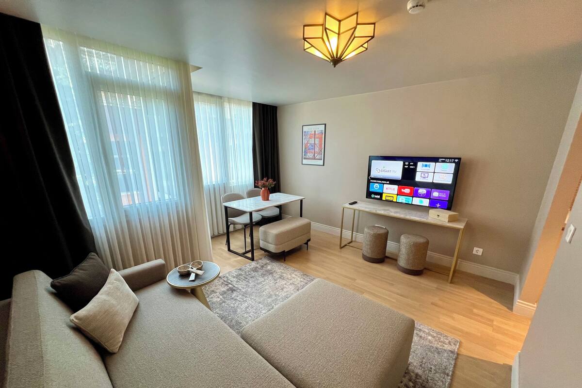 Una sala de estar moderna con un sofá, una mesa de centro, un televisor y un comedor con una mesa y sillas.