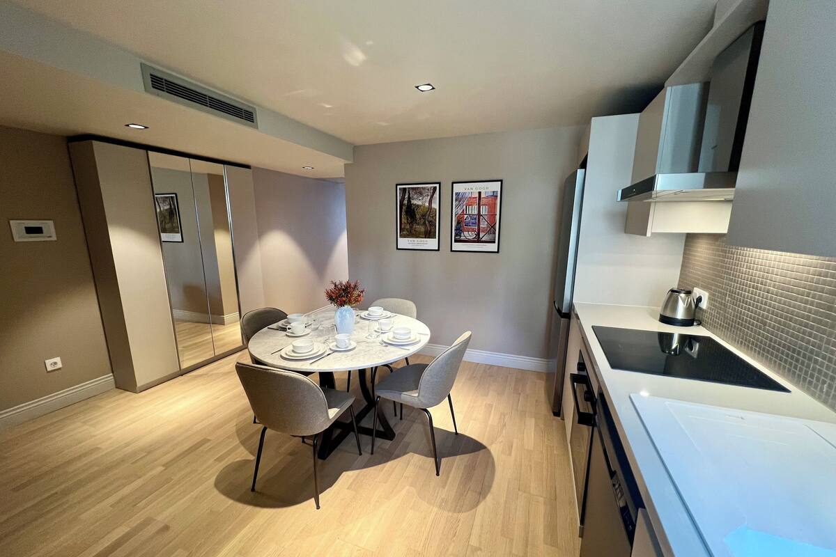 Una cocina moderna con comedor, con una mesa redonda dispuesta para cuatro personas, una tetera y un microondas.