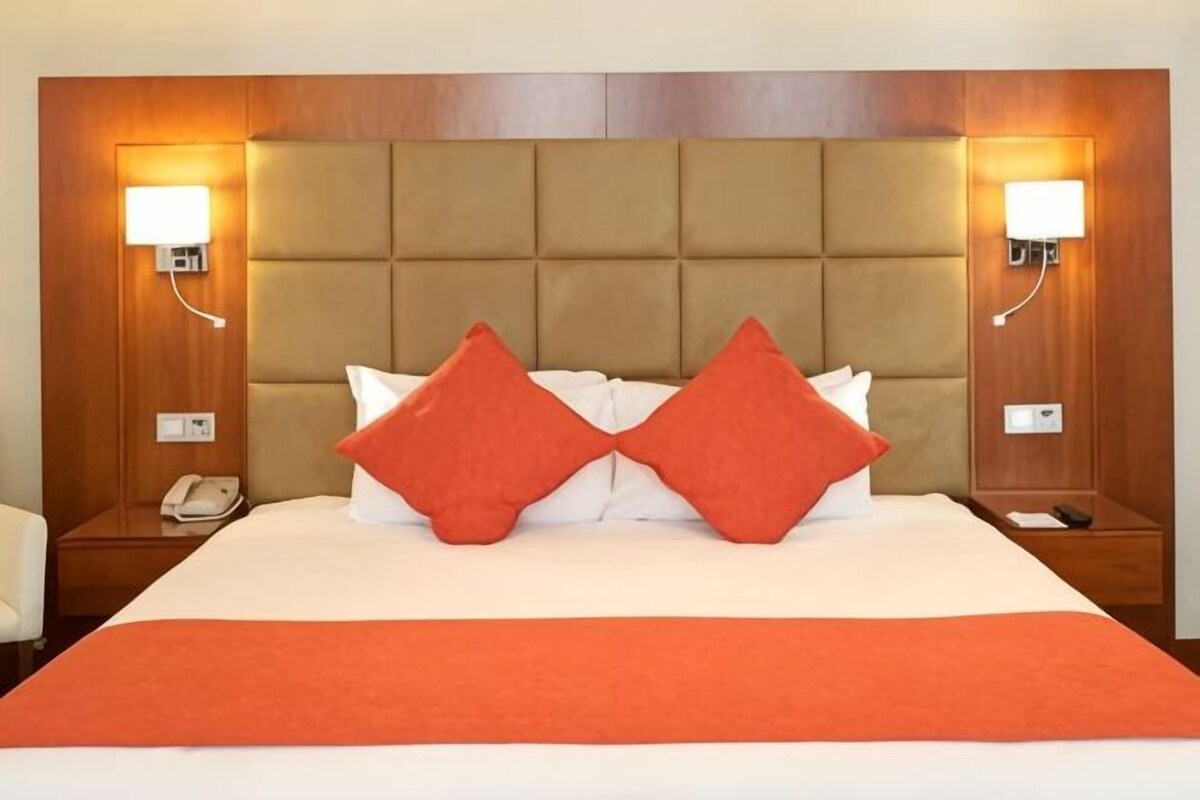 Ein Hotelzimmer mit einem großen Bett, zwei Nachttischen und einem Holzkopfende.