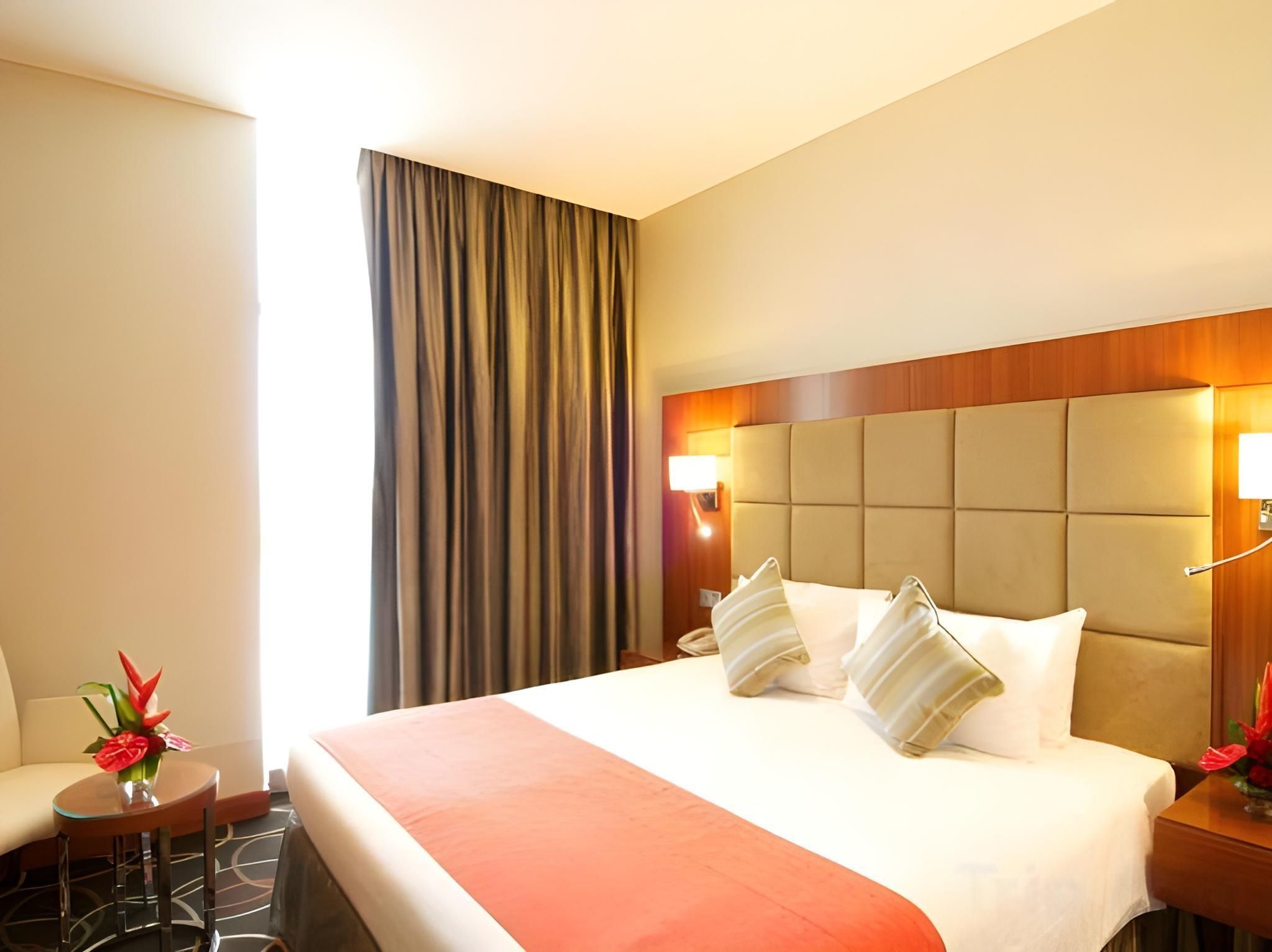 A hotel room with a large bed, a bedside table, a chair, and a view of the outside.