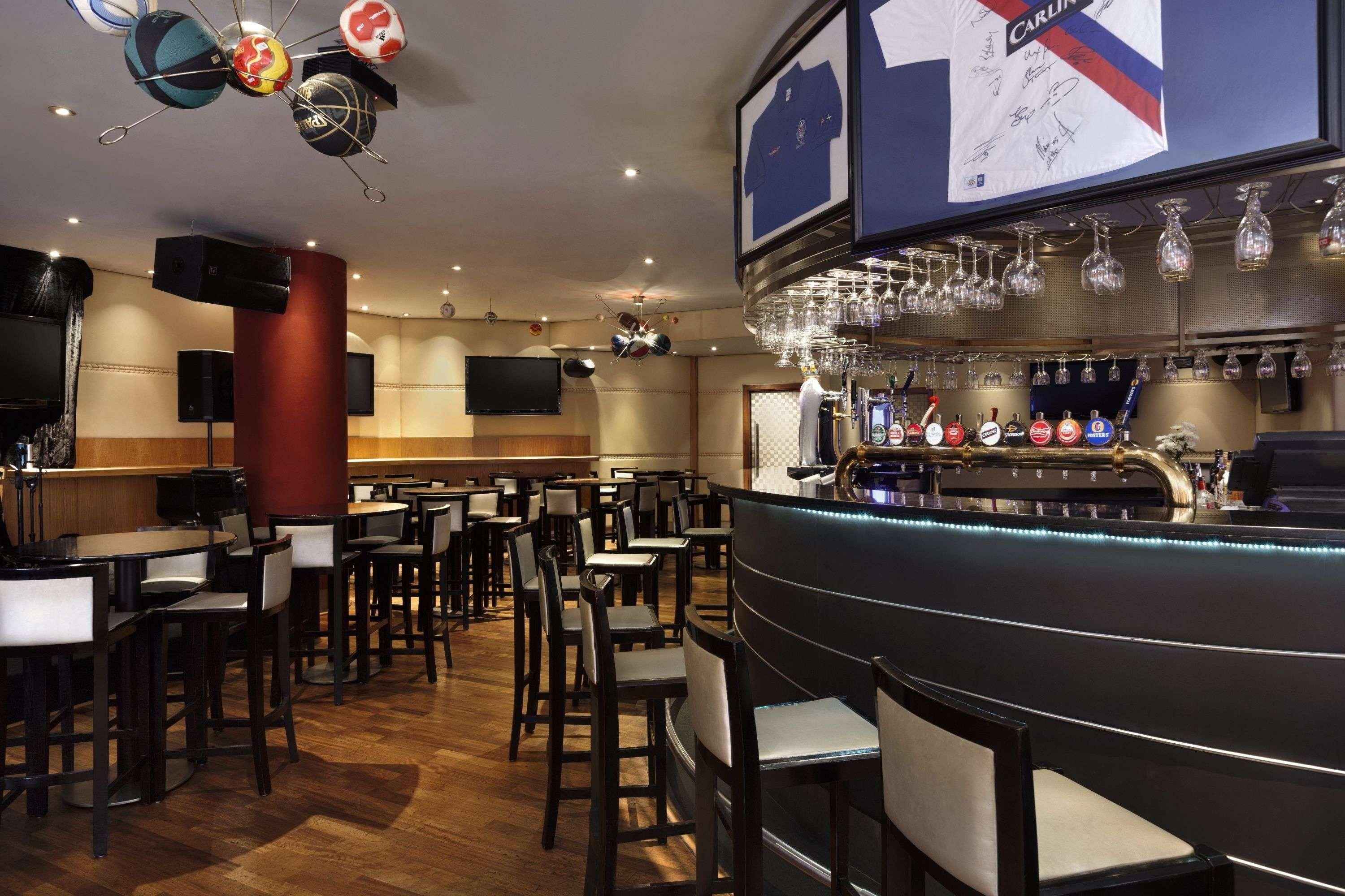 Un espace bar offrant différentes options de sièges, un comptoir avec un large choix de bières à la pression et un téléviseur fixé au mur.