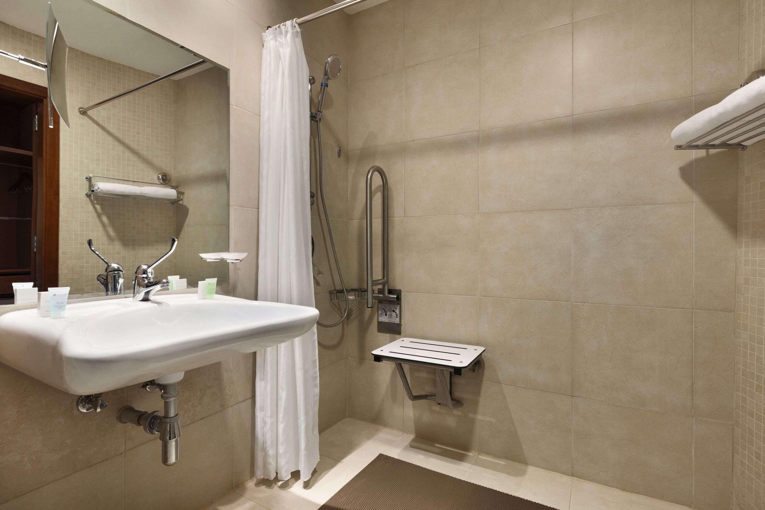 A bathroom with a shower, a sink, and a towel rack.