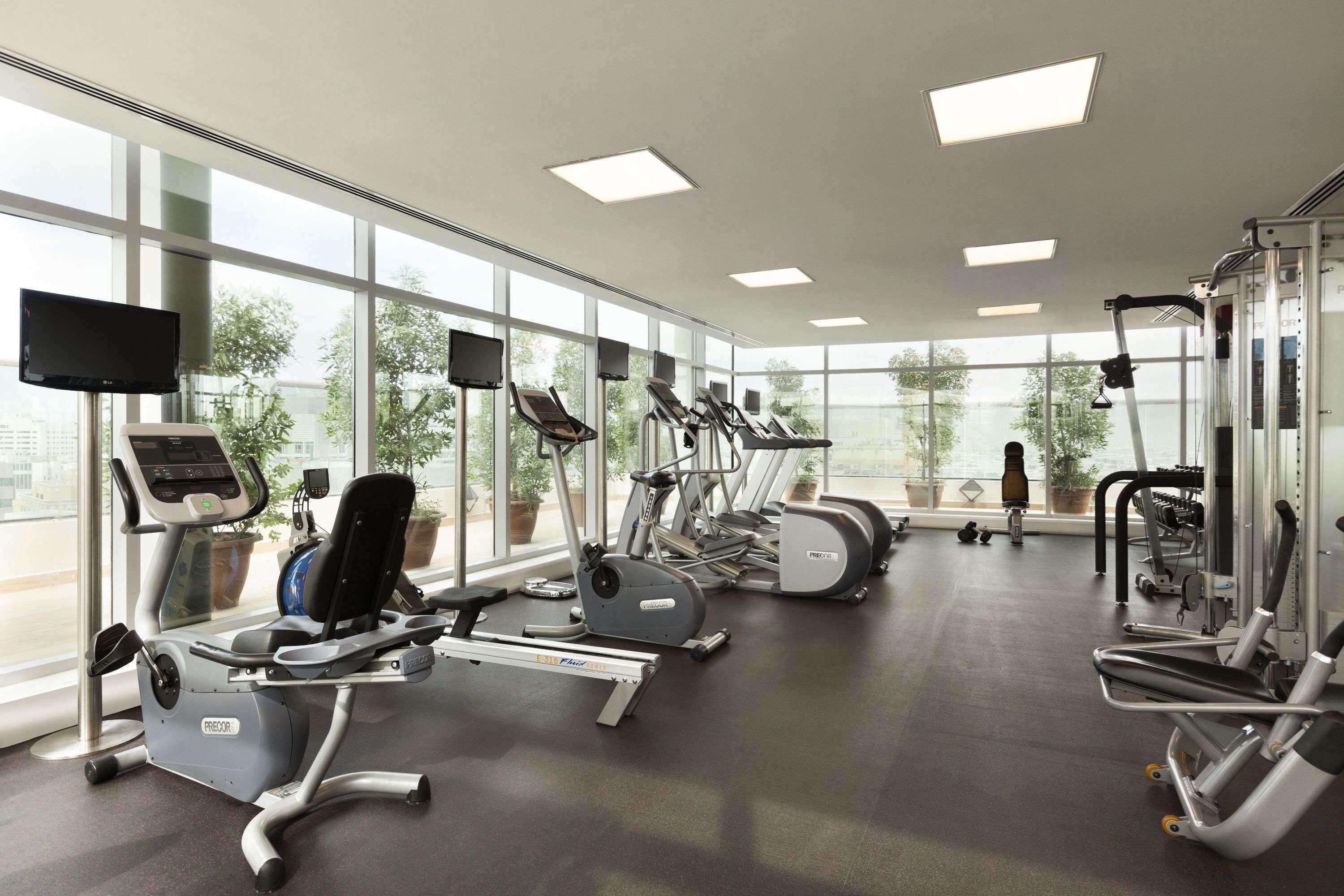 A gym with various exercise equipment, large windows, and a flat-screen TV.