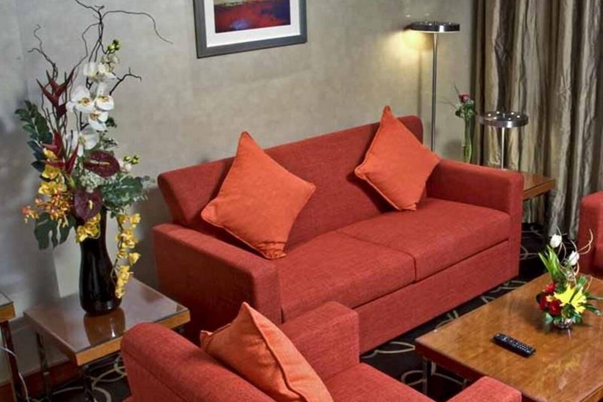 Un sofá rojo con cojines a juego, un jarrón de flores y un cuadro en la pared.