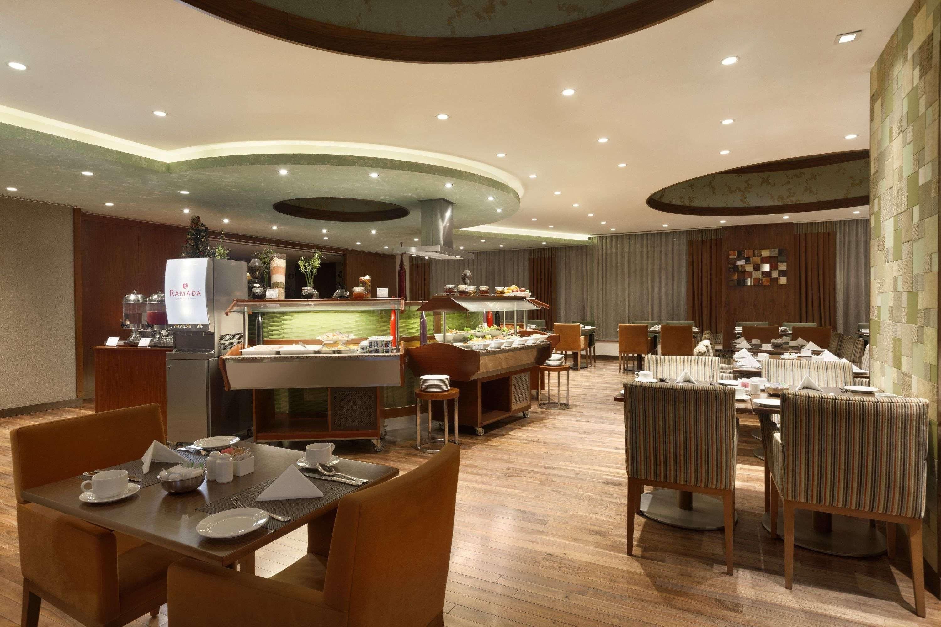 Un restaurante con barra de desayuno tipo buffet, mobiliario de madera y un diseño de techo moderno.