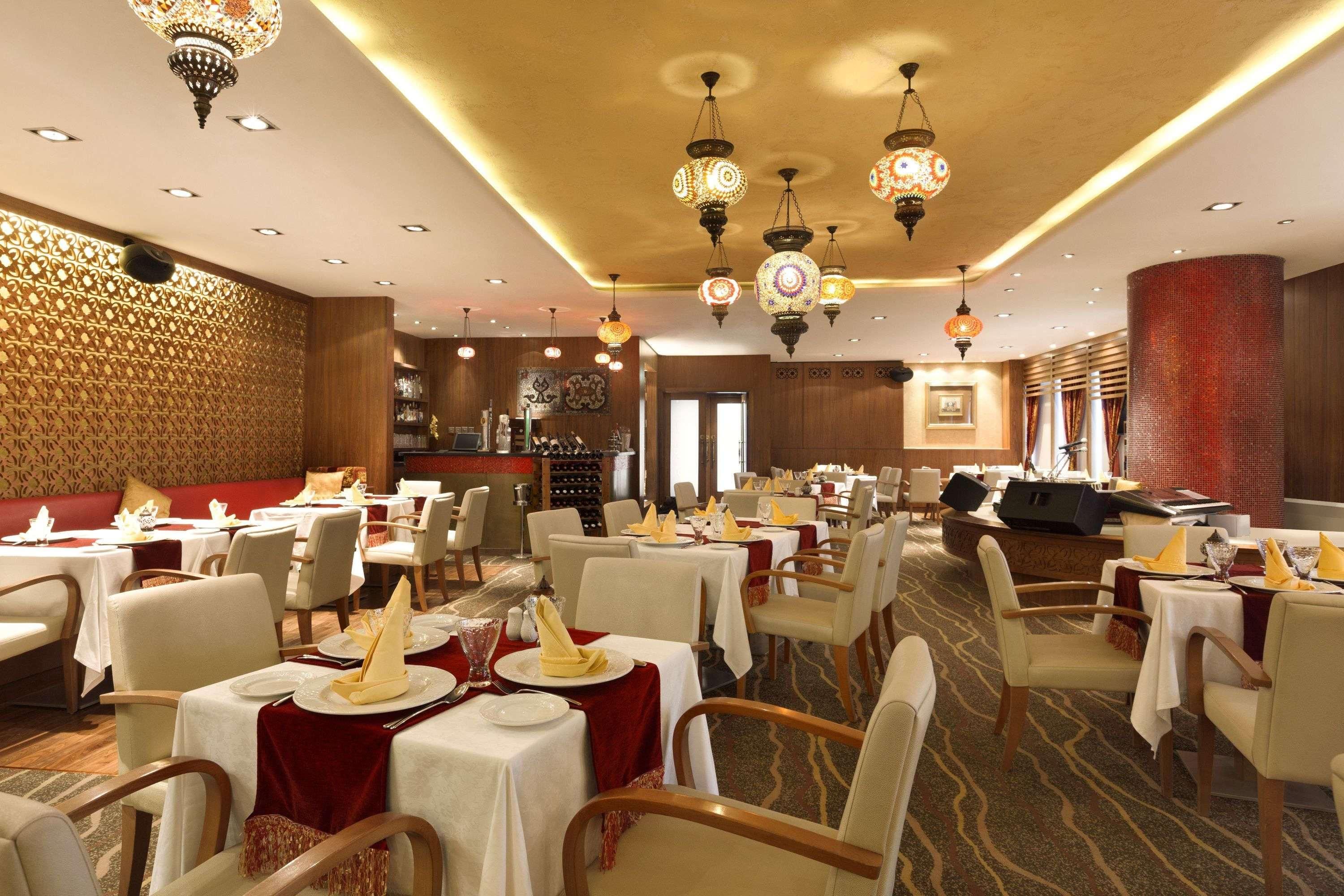 Un restaurante con varias mesas, candelabros y un muro con estampado.