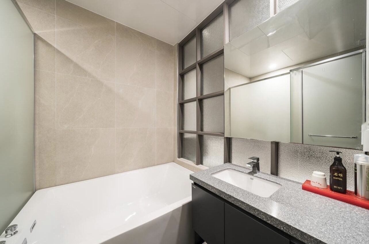 A modern bathroom with a bathtub, a sink, and a large mirror.