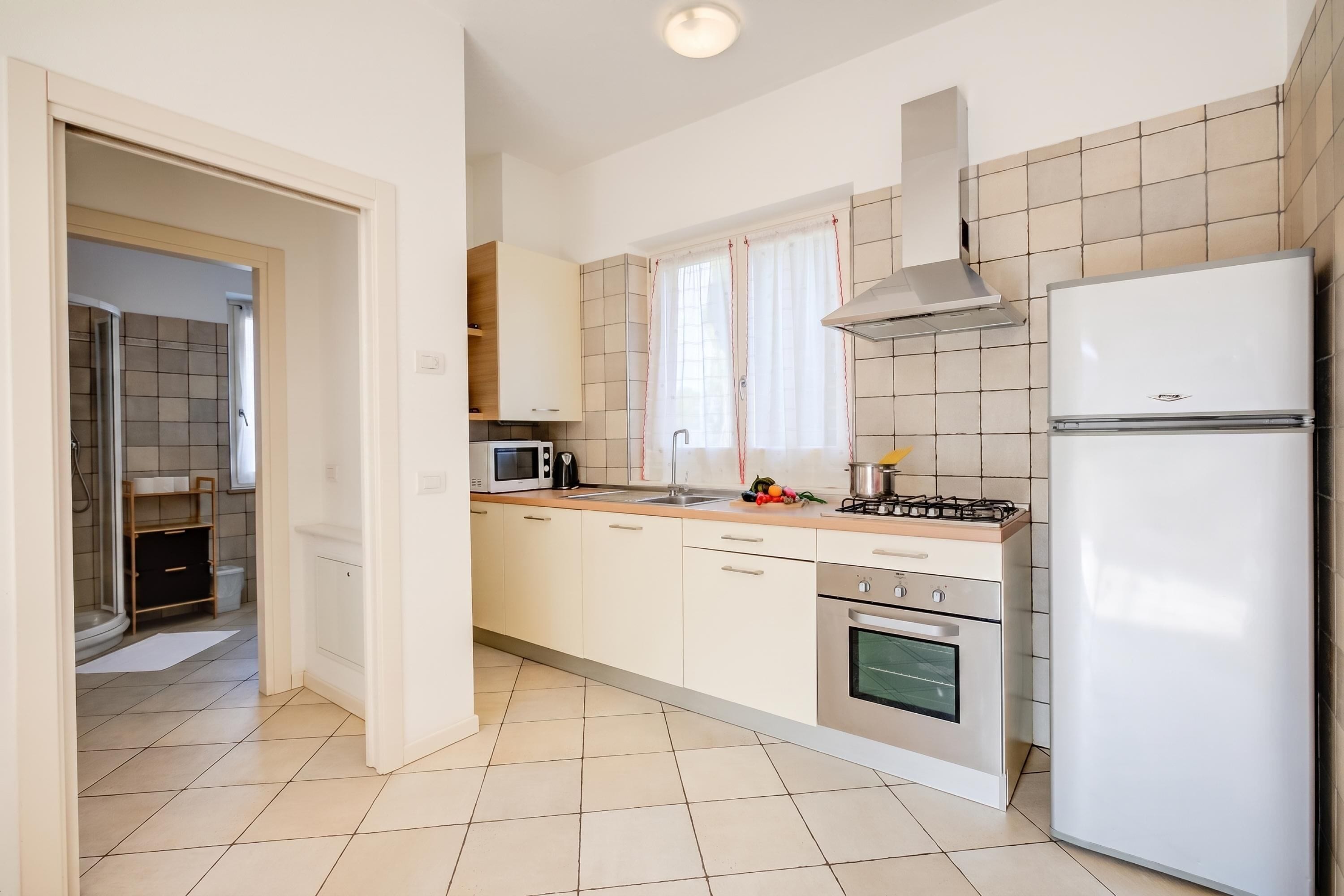 A modern kitchen with white cabinets, a stainless steel stove, a microwave, and a refrigerator.