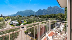 A balcony with a view of mountains, parked vehicles, and greenery. - Casa al Cor Apartments (Nago-Torbole)