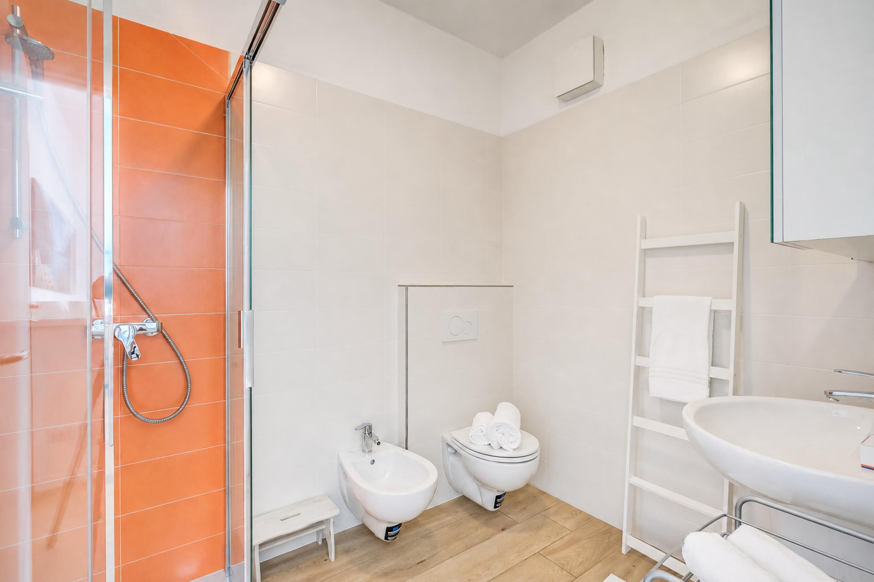 A bathroom with a shower, bidet, toilet, and sink.