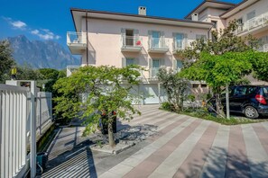 Un edificio residencial de varios pisos con balcones, un patio empedrado y montañas al fondo.