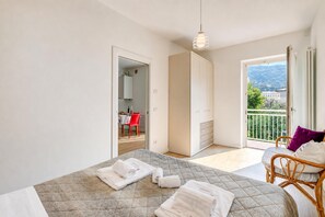 A bedroom with a bed, a chair, a balcony, and a view of the outside. - Casa al Cor Apartments (Nago-Torbole)