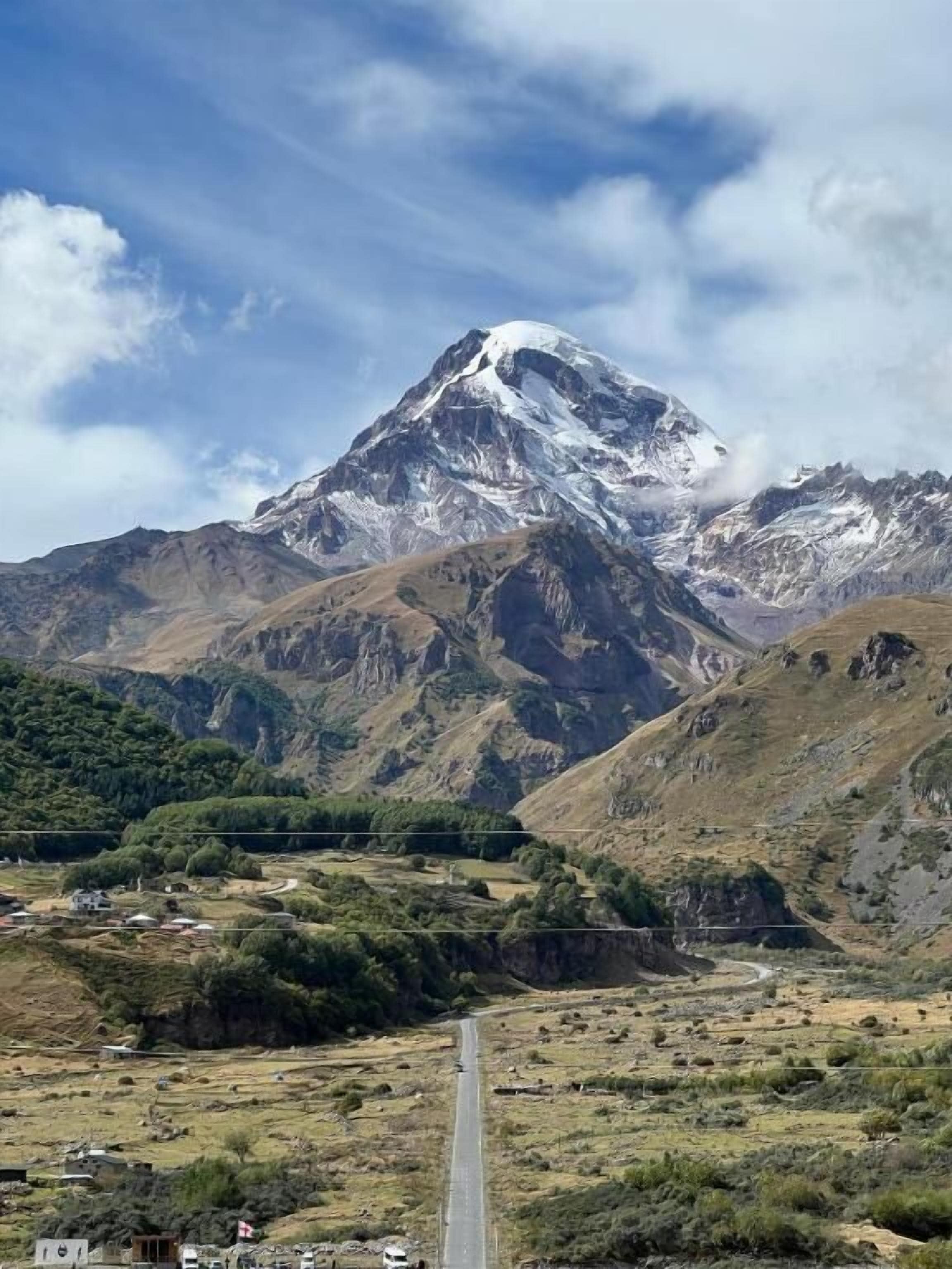 A mountain landscape with a road leading towards a village.