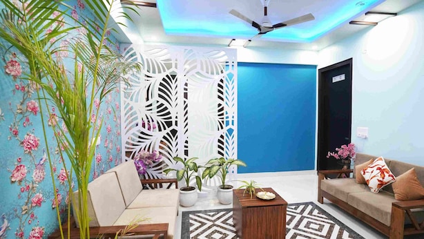A modern living room with a sofa, coffee table, and decorative plants. - Mansavi Villa HomeStay (Greater Noida)