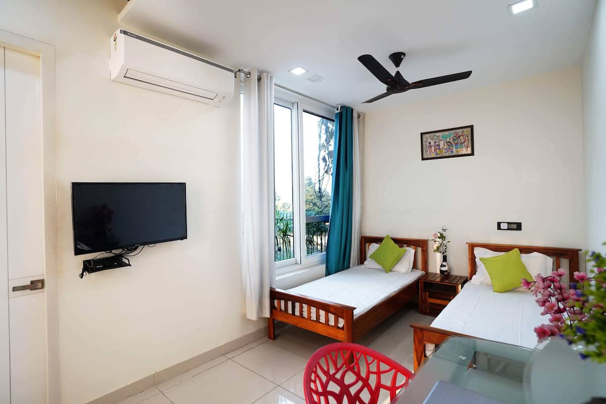 Une chambre à coucher avec un lit, une télévision, un ventilateur de plafond et une fenêtre avec des rideaux.