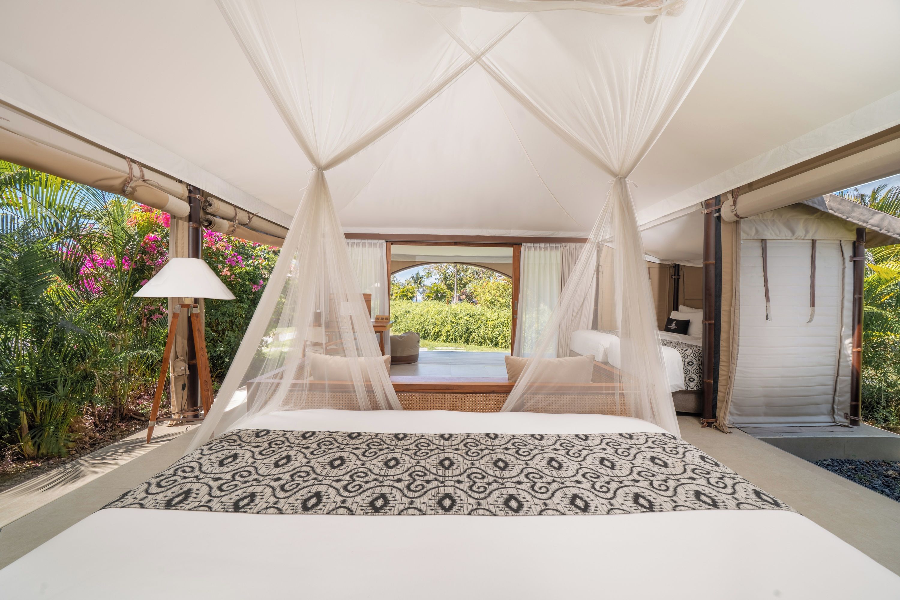 Un dormitorio con cama con dosel, vistas al jardín y una habitación separada con cama.