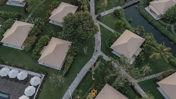 Vue aérienne d’un complexe hôtelier comprenant plusieurs hébergements de type bungalow, une fontaine centrale et des jardins bien entretenus.
