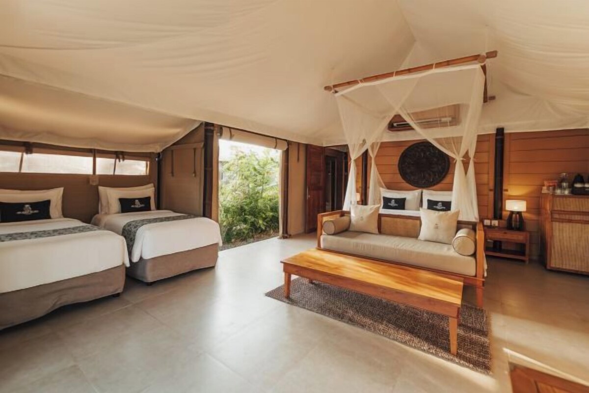 A tented room with two beds, a sofa, and a wooden coffee table.