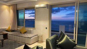 Ein modernes Wohnzimmer mit einer Couch, Sesseln und Meerblick.